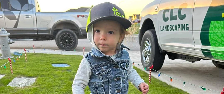 CLC child posing by work truck wearing branded hat in New Braunfels, TX.