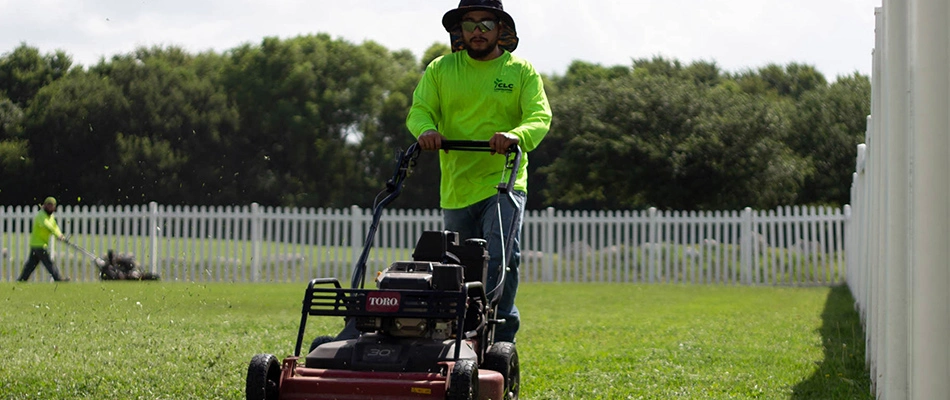 A CLC professional mowing for a customer with a push mower in New Braunfels, TX.