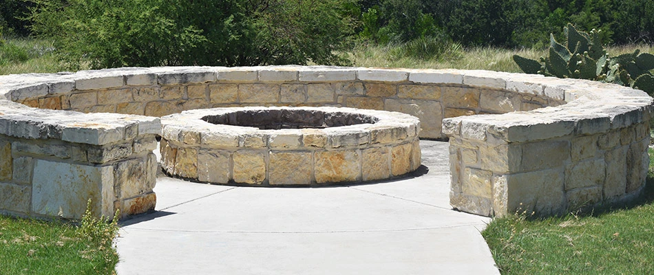 A stone fire pit surrounded by a retaining wall in San Marcos, TX.
