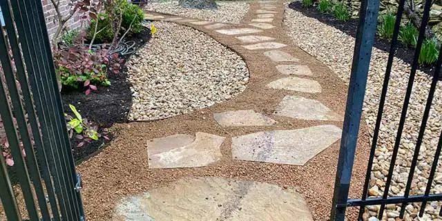 Natural stone walkway built through rock mulch landscape beds in Seguin, TX.