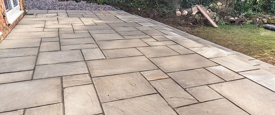 A modern patio made from pavers with a bit of dirt on it in Buda, TX.