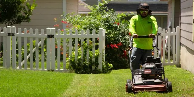 CLC Landscaping worker mowing a yard in New Braunfels, TX.