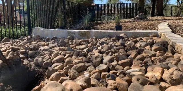 River rock mulch installed in a landscape bed near Kyle, TX.