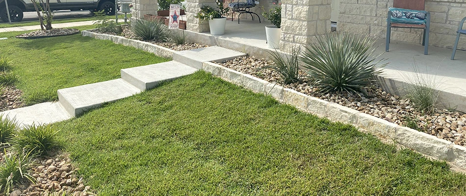 A short white retaining wall surrounding a landscape bed in front of a home in Seguin, TX.