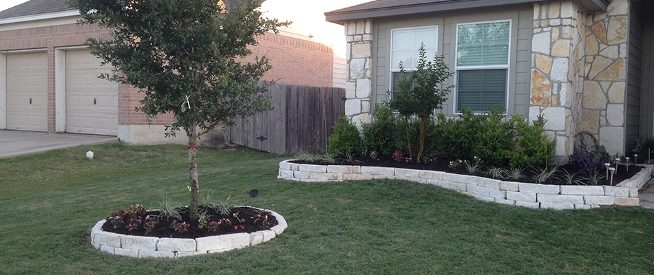 White stone retaining wall installed for 2 landscape beds for a home in Woodcreek, TX.