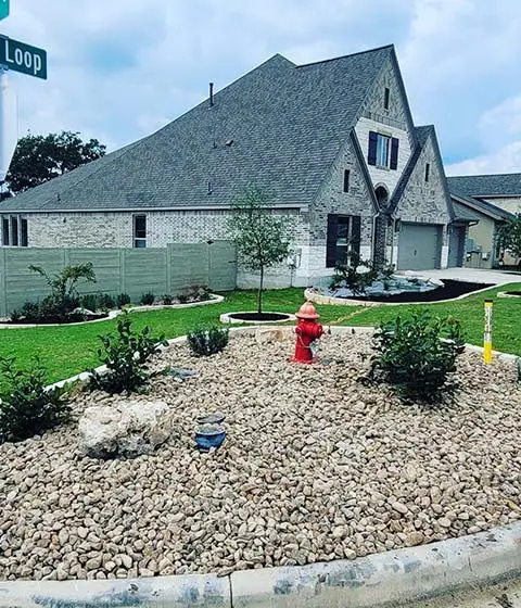 Rock mulch landscape bed and plantings beside a home in New Braunfels, TX.